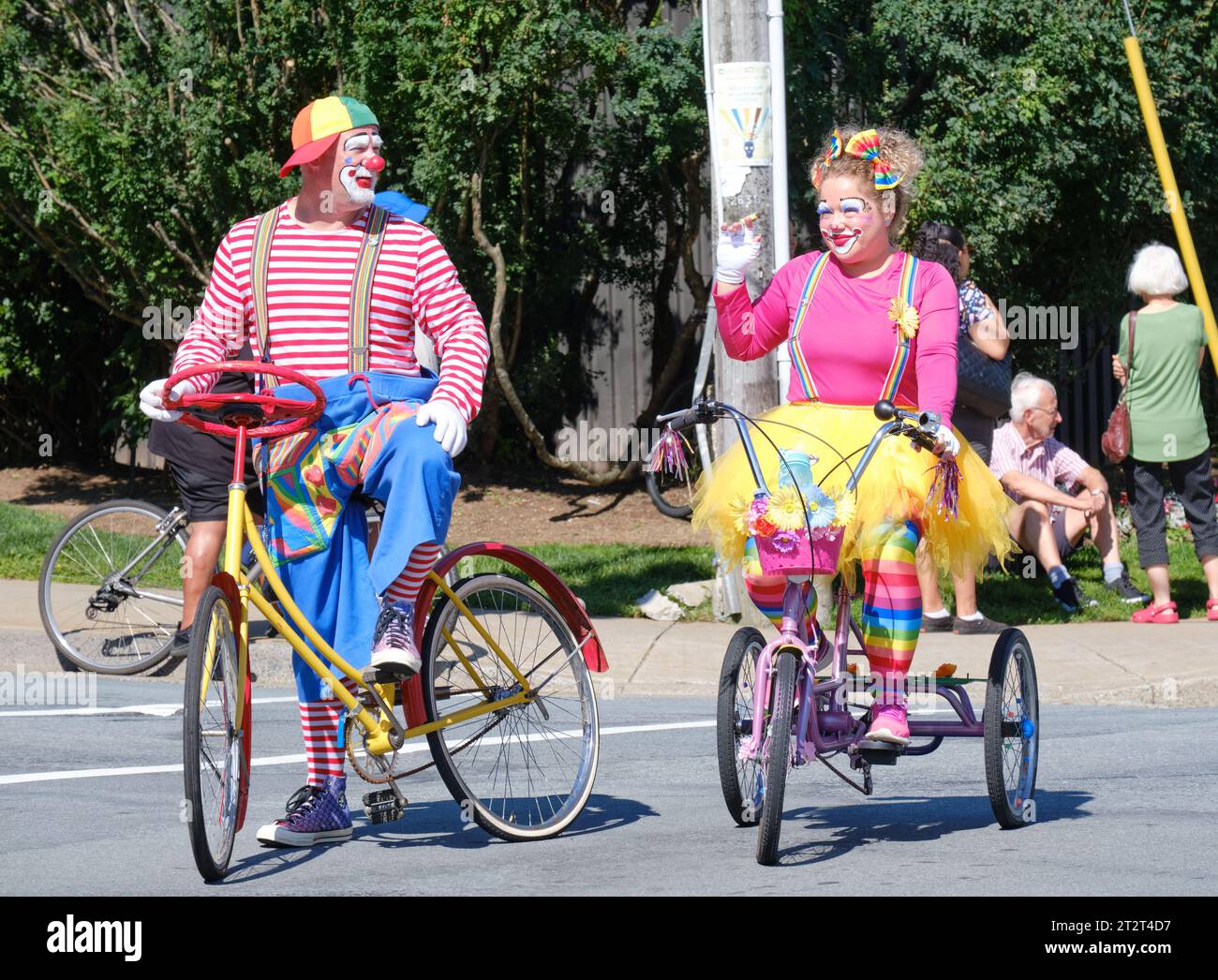 clowns on tricycle riding parade waving at crowd Stock Photo Alamy