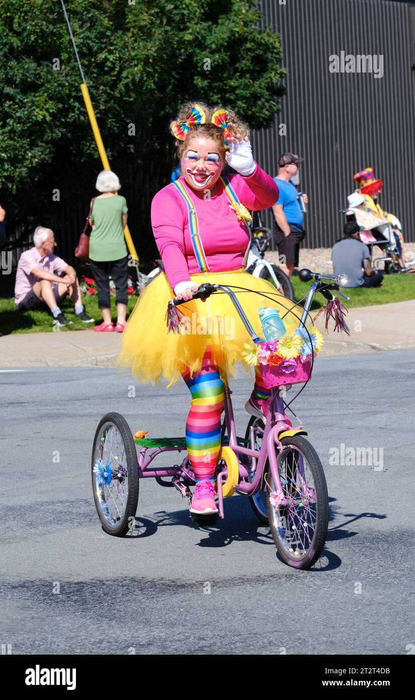 clowns on tricycle riding parade waving at crowd Stock Photo Alamy