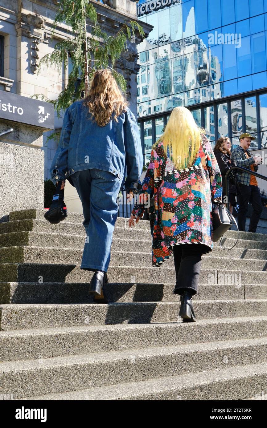 two people in fashionable outfit seen from behind walking up concrete stairs in central vancouver Stock Photo