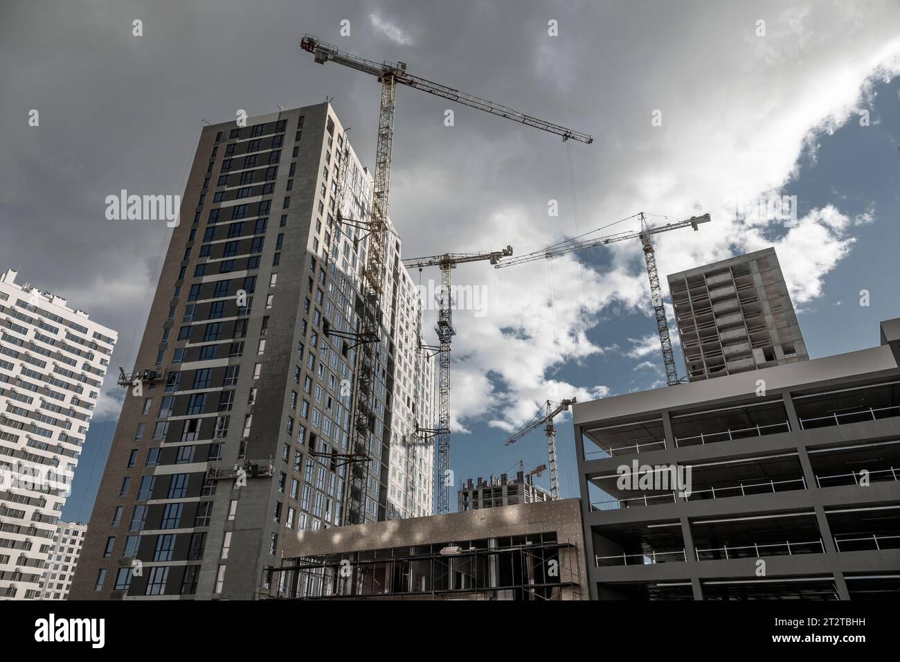 Concrete constructions and cranes on the construction site, wide angle dynamic shot, bottom view. Stock Photo