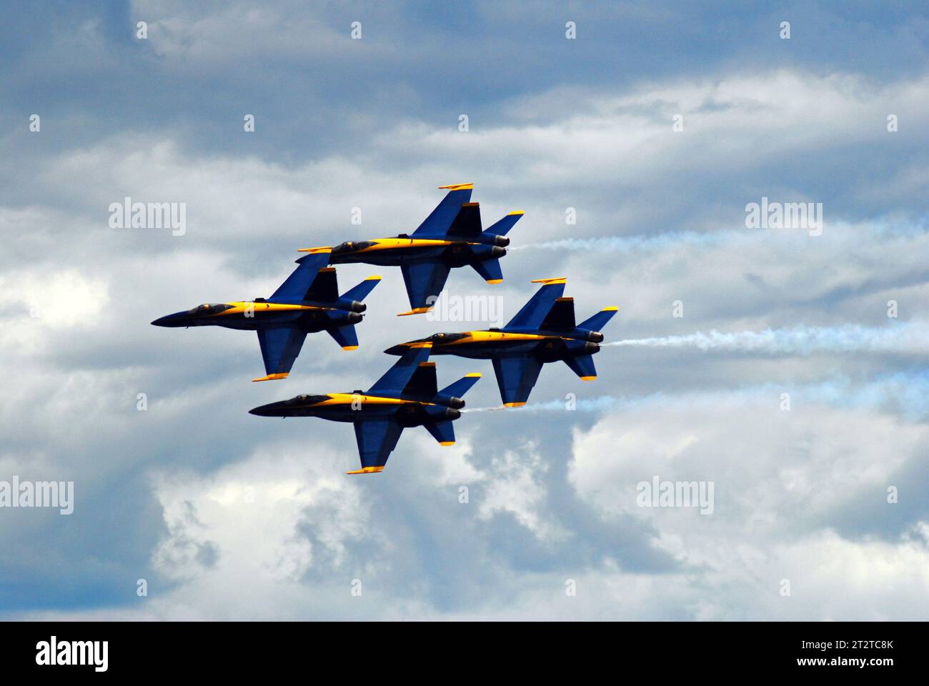 A group of four Blue Angels jet planes fly close together in a diamond formation at an airshow Stock Photo