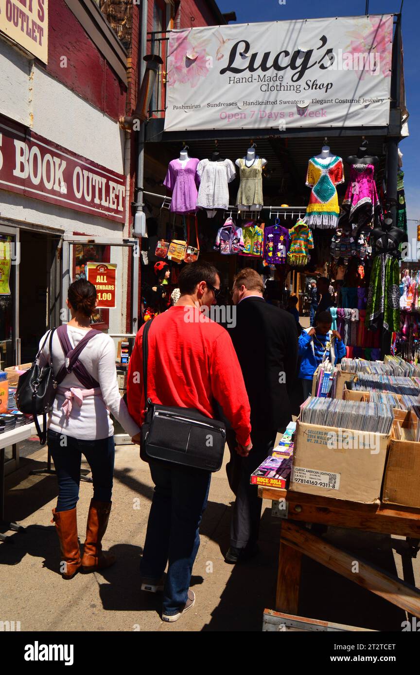 People shop along the sidewalk of the Strip District in Pittsburgh seeking bargains with vintage clothes and used books Stock Photo
