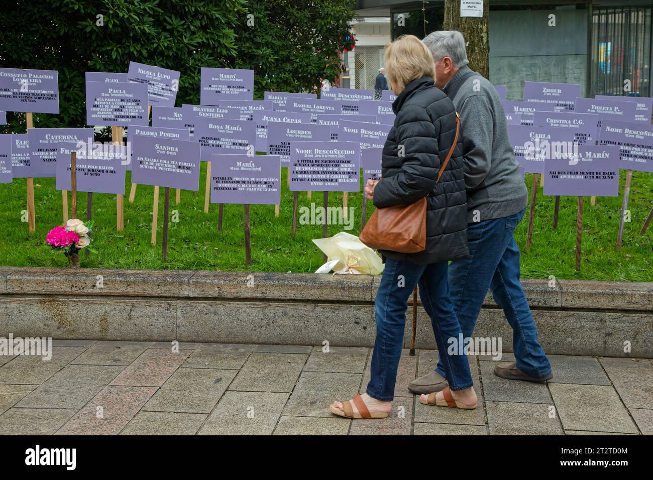LUGO, October 4, 2023 : An old couple walks in front of posters against femicide rates in Spain Stock Photo
