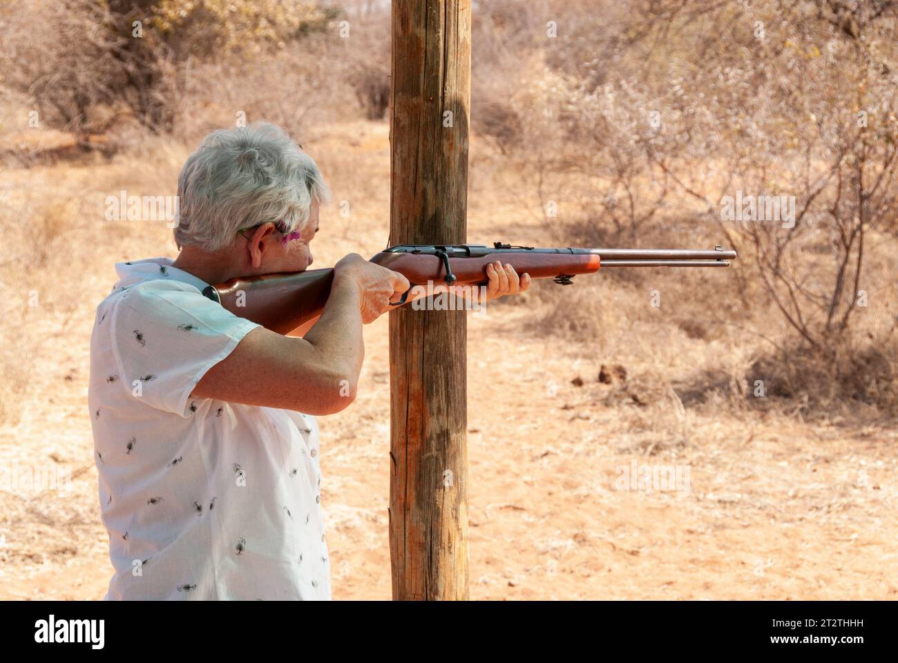 An old lady takes aim with a rifle at a hunting farm in South Africa Stock Photo