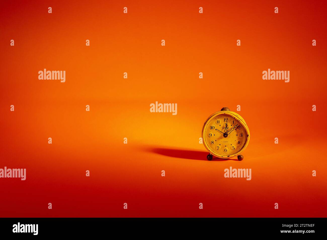 Old clock with a bold shadow in a orange background Stock Photo