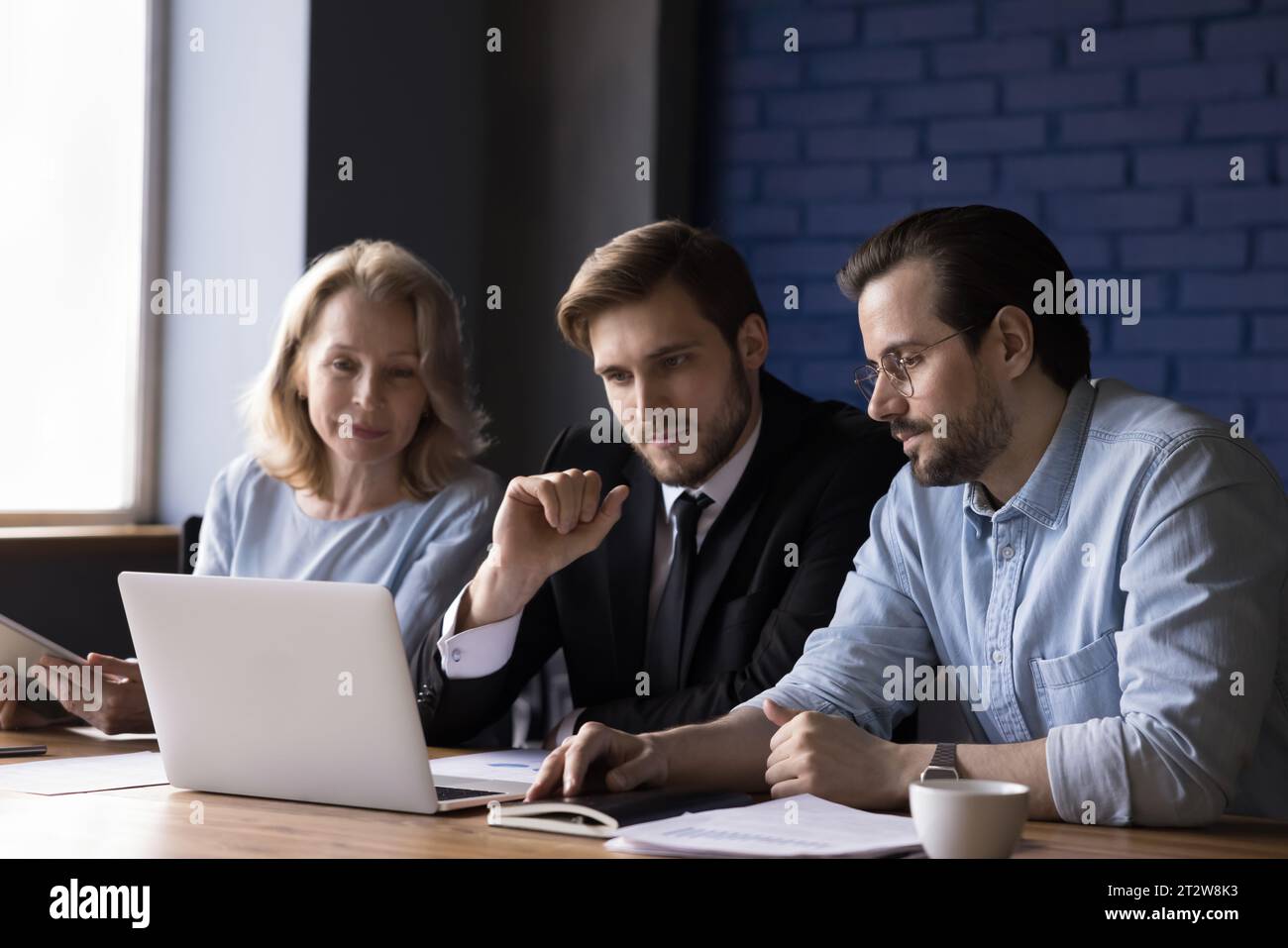 Three teammates working together use laptop in office Stock Photo