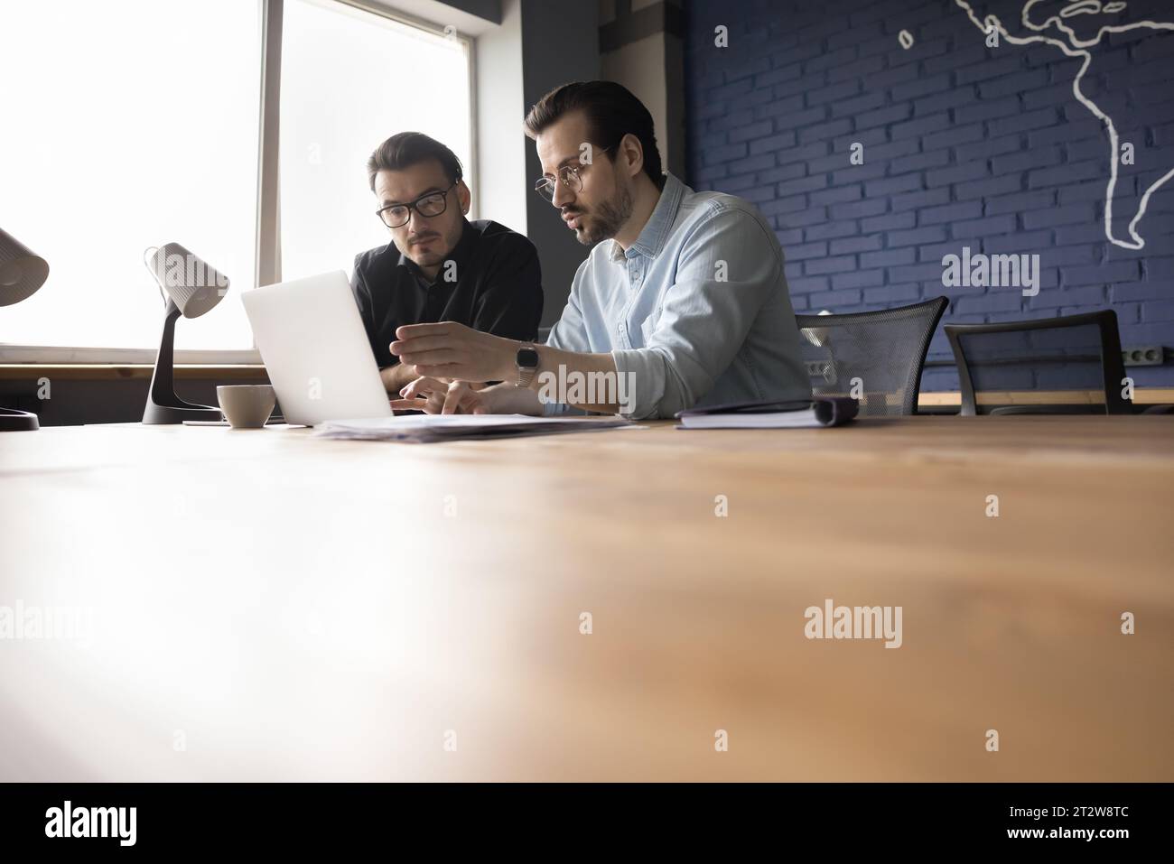 Two businessmen working together on project using laptop at workplace Stock Photo
