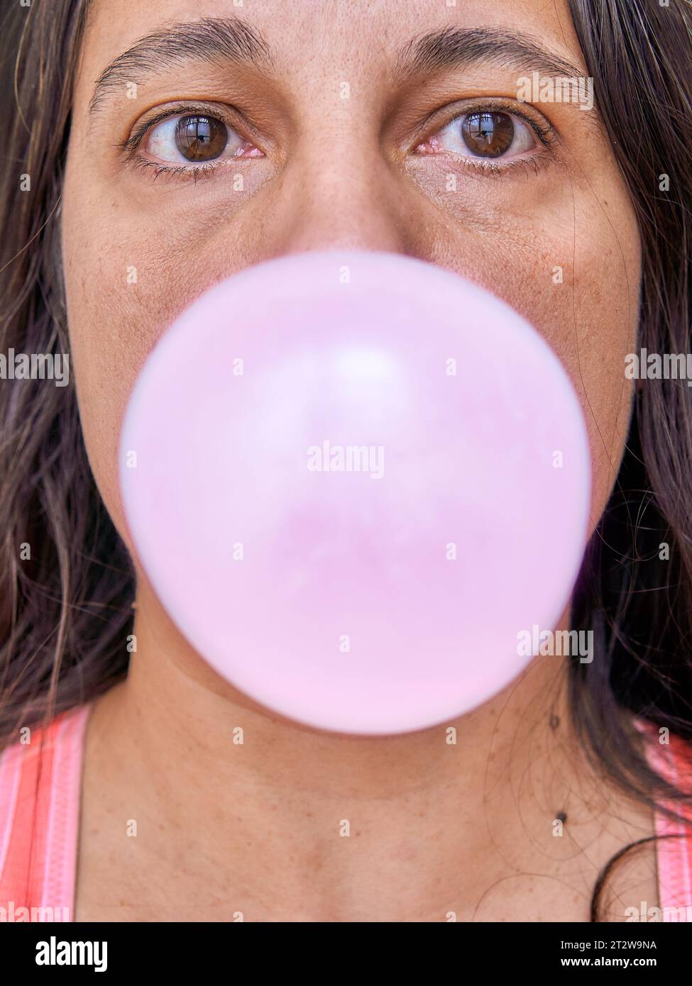 Mid adult woman making a balloon with chewing gum Stock Photo