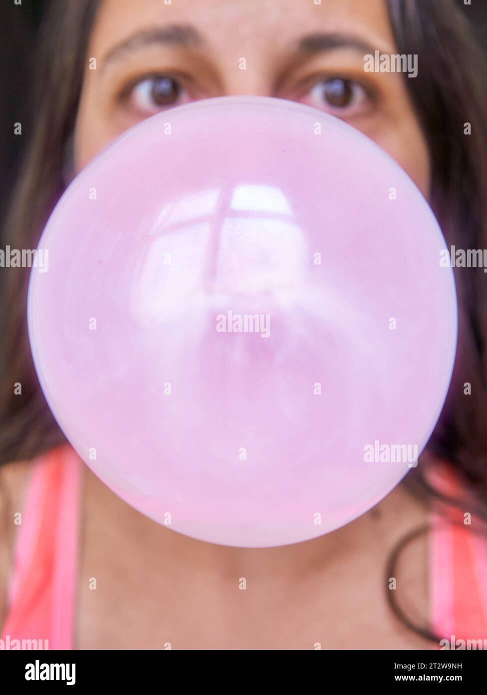 giant bubble gum balloon about to exlplode on mid adult woman face Stock Photo