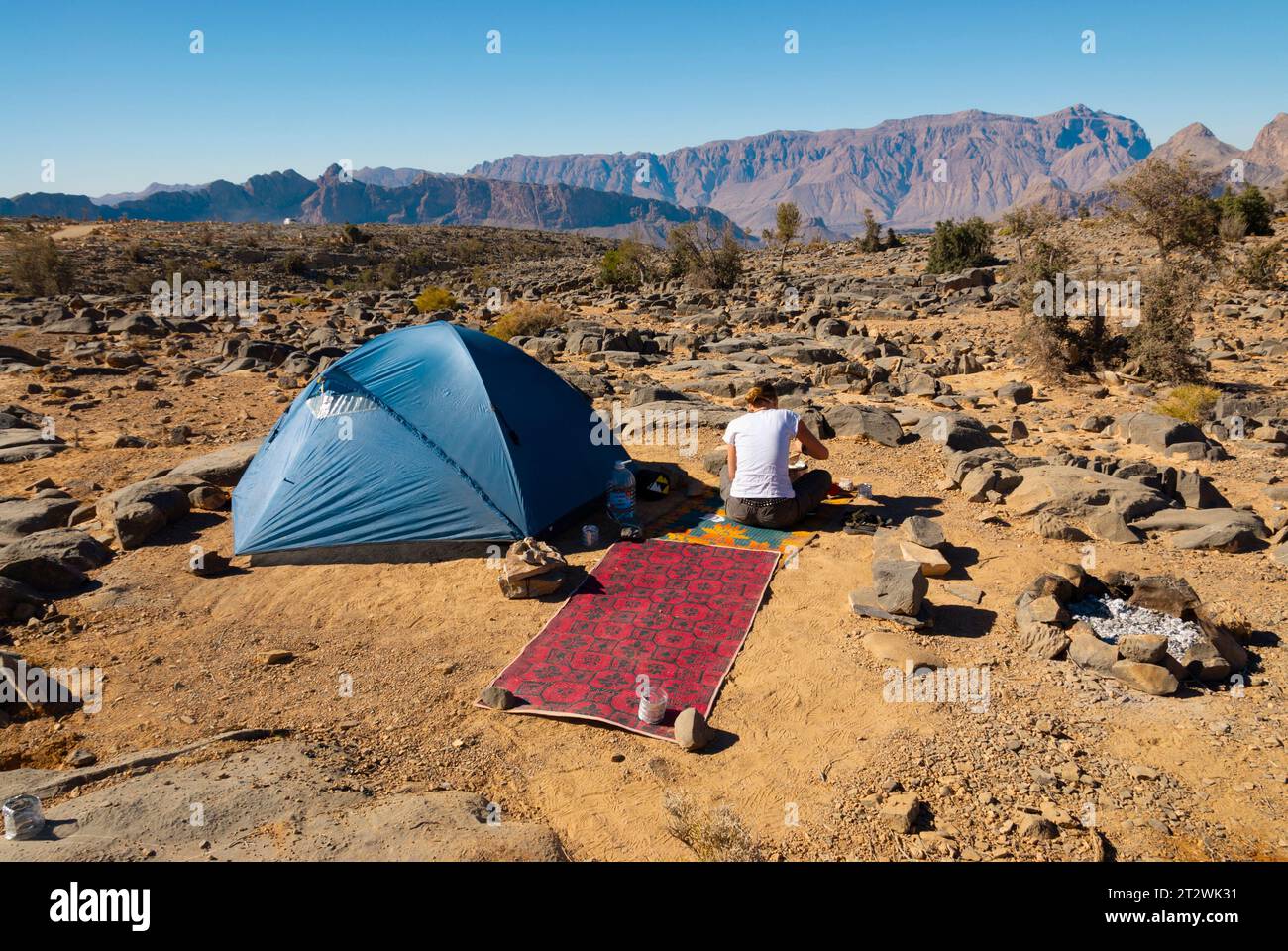 A woman sits at a wild campsite on the top of Jebel Shams in the Al Hajar mountains of Oman Stock Photo