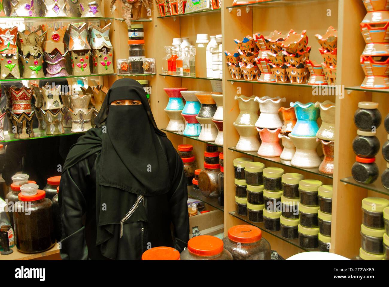 A woman wearing full traditional clothing sells products at a small shop in Salalah in the south of Oman Stock Photo