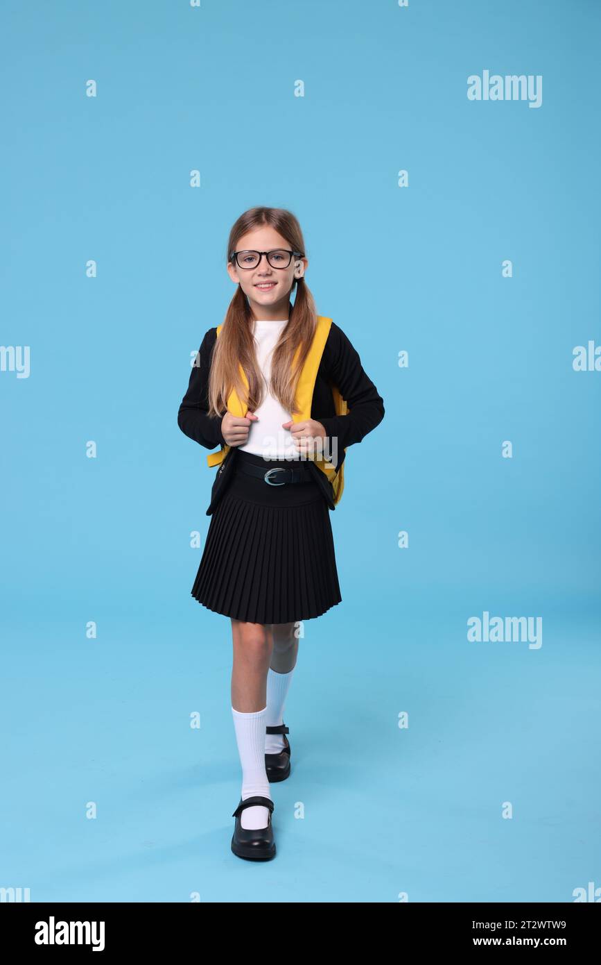 Happy schoolgirl with backpack on light blue background Stock Photo - Alamy