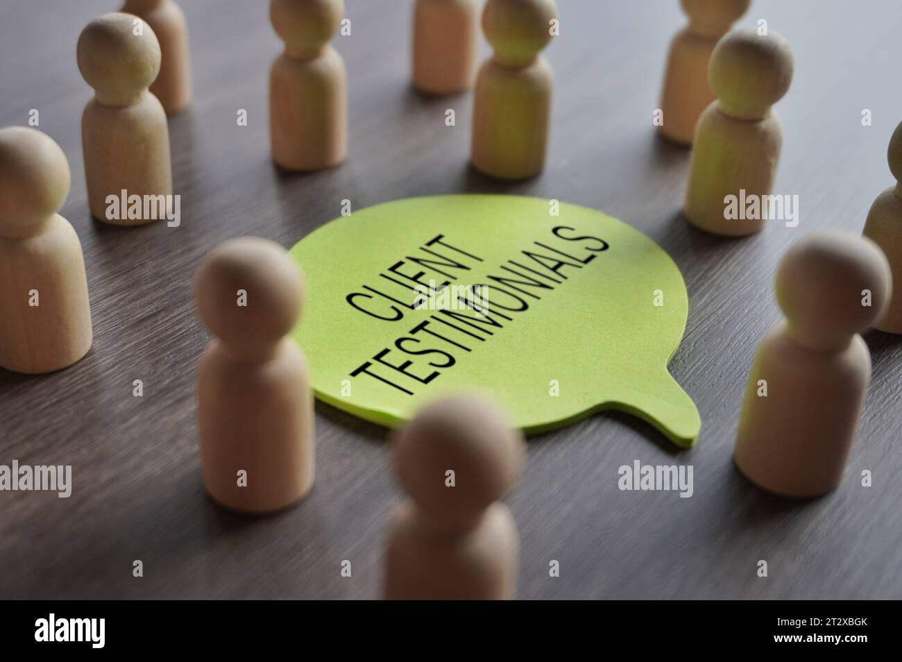 A group of wooden figurines surrounding a speech bubble with text CLIENT TESTIMONIALS. Business, feedback concept Stock Photo