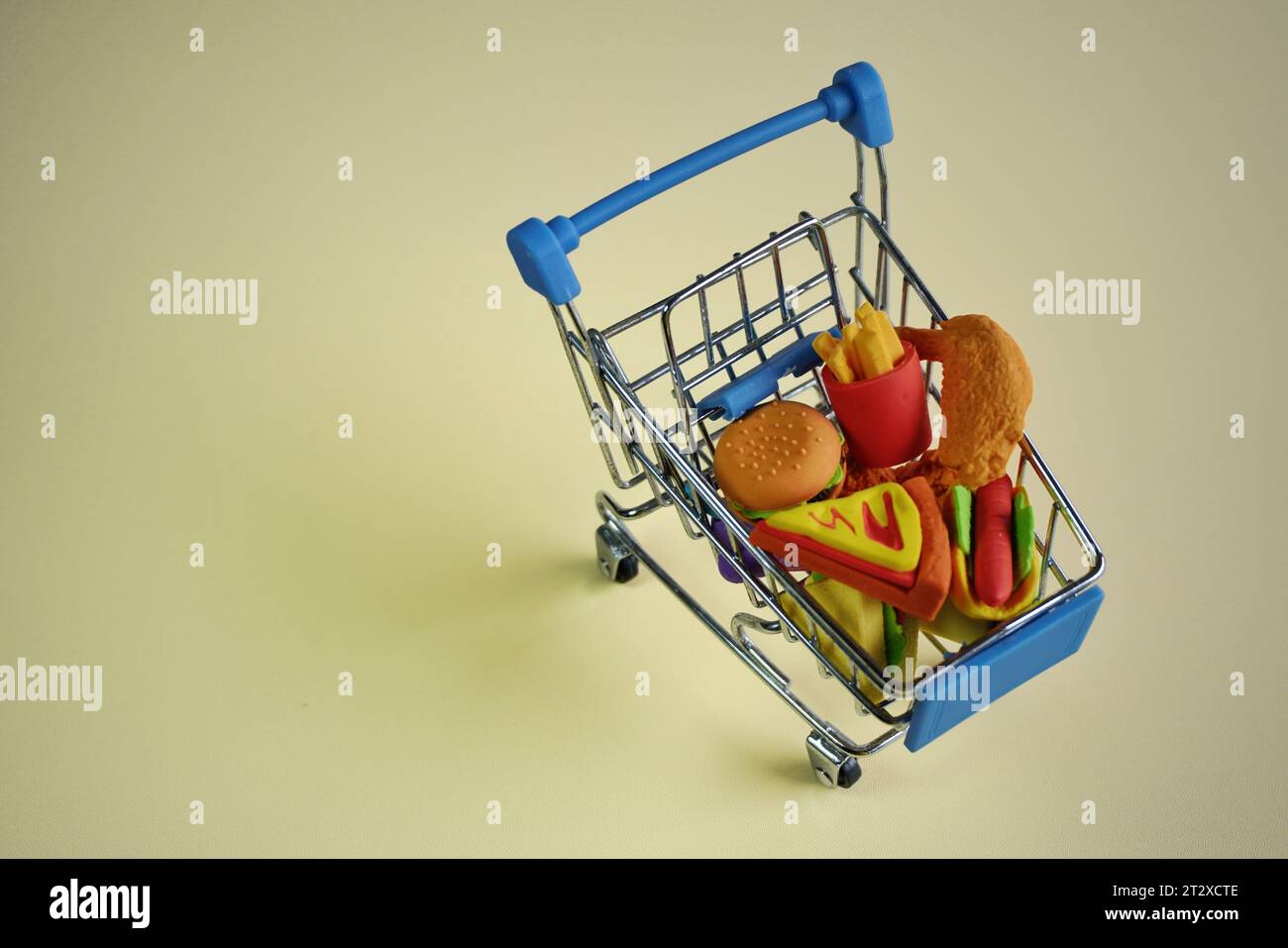 Closeup image of shopping cart full with junk foods like burger, fries and pizza. Copy space for text. Bad eating habits concept. Stock Photo