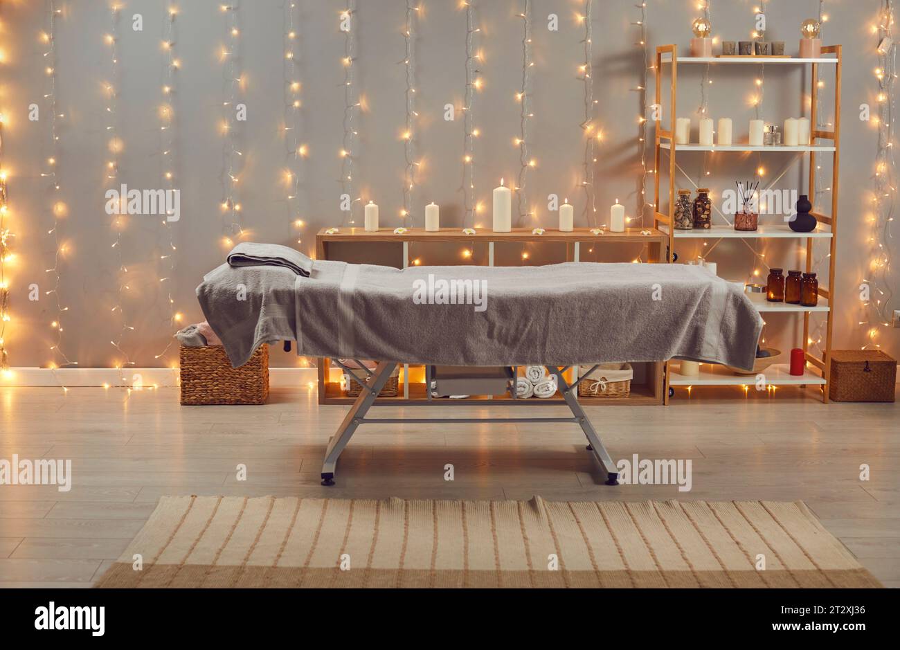 Spa salon interior with massage bed, burning candles and lights Stock Photo