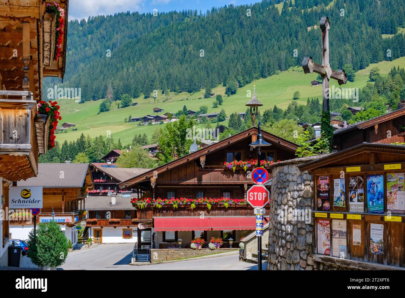 The centre of sloping Alpbach Village, traditional Alpine architecture, flowers on balconies, meadows, tall trees. Tyrol, Austria. Stock Photo