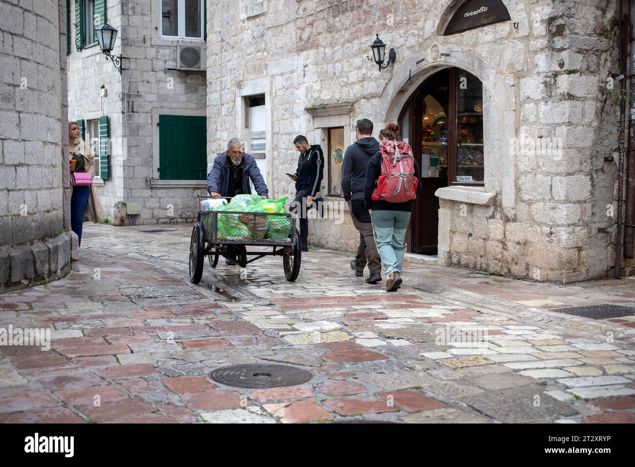 Montenegro, April 15, 2023: Man pushing a delivery tricycle down the cobblestone street of Kotor Old Town Stock Photo