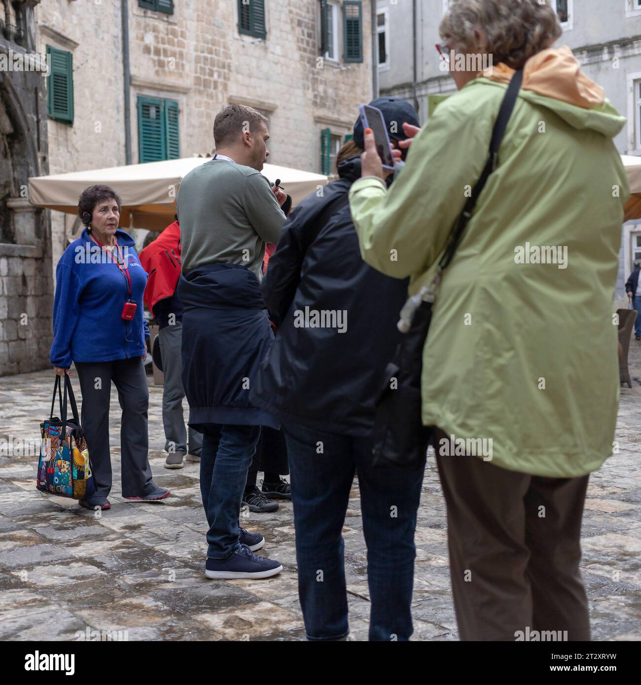 Kotor, Montenegro, Apr 17, 2023: A group of tourists gathered around guide at the Flour Square in Old Town Stock Photo