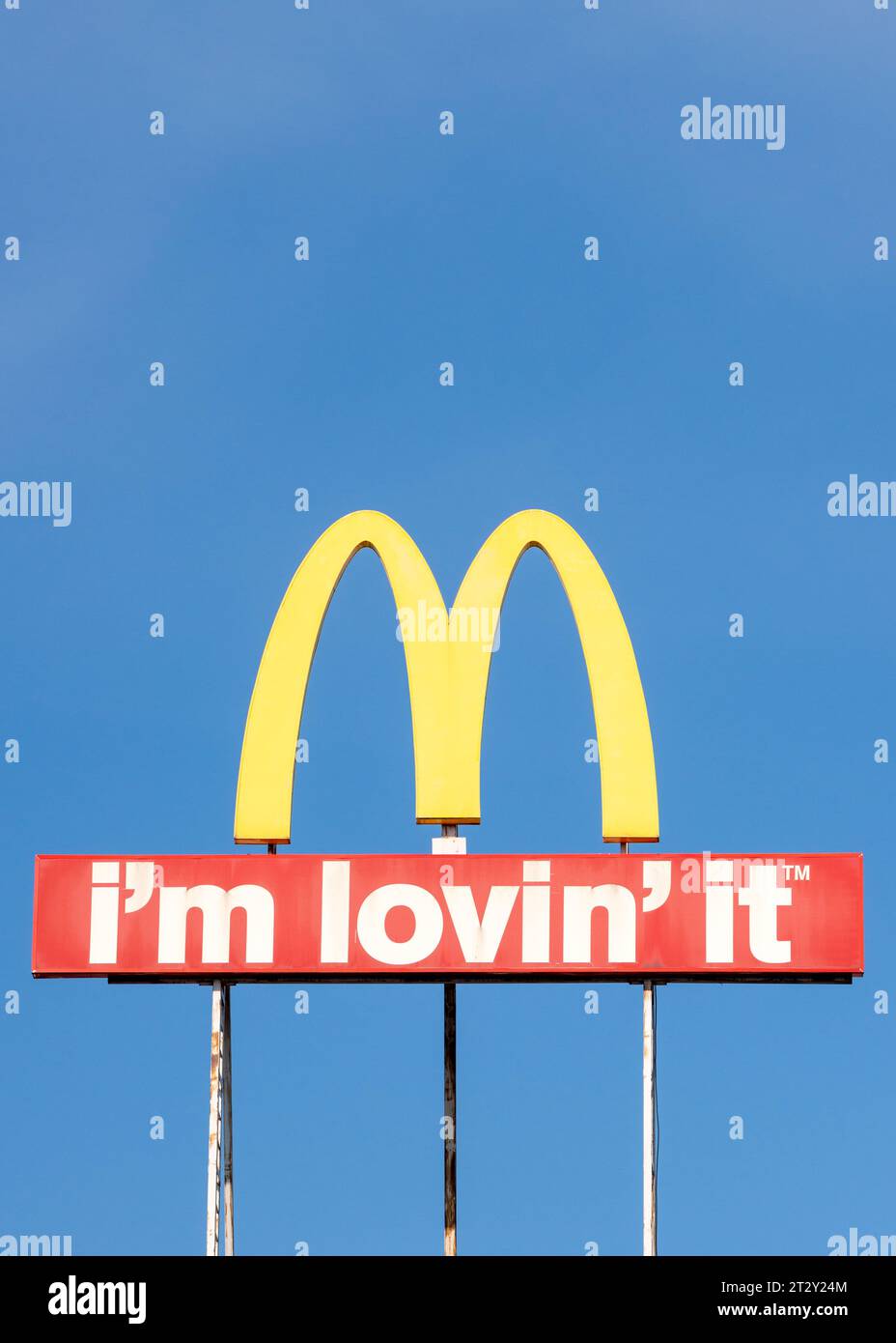 McDonald's logo arches sign and I'm Lovin' It slogan against blue sky Stock Photo