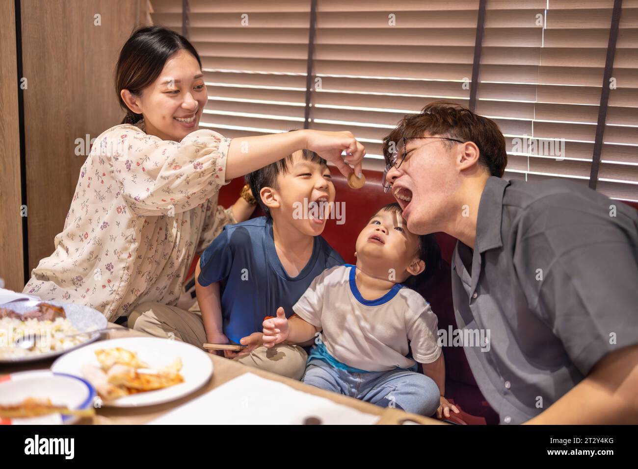 Happy mother feeds her family in restaurant Stock Photo