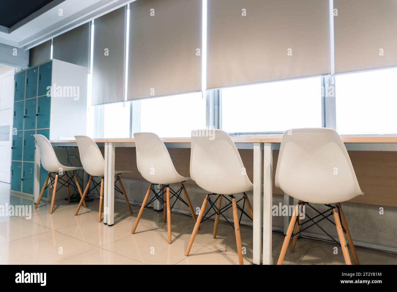 Office interior. Meticulously arranged white chairs on a chic and cozy desk Stock Photo