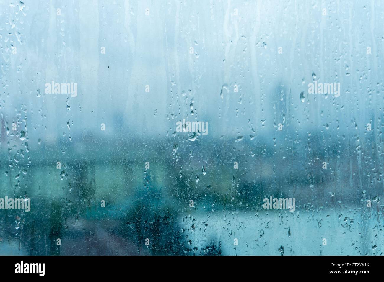 Glass window bearing rainwater traces with hazy tall building scenery ...