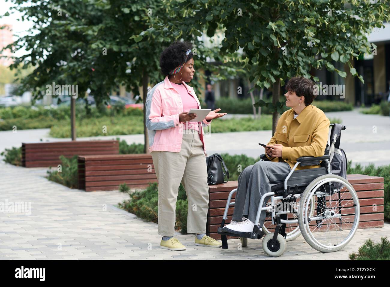 Multiethnic couple using gadgets while spending time outdoors Stock Photo