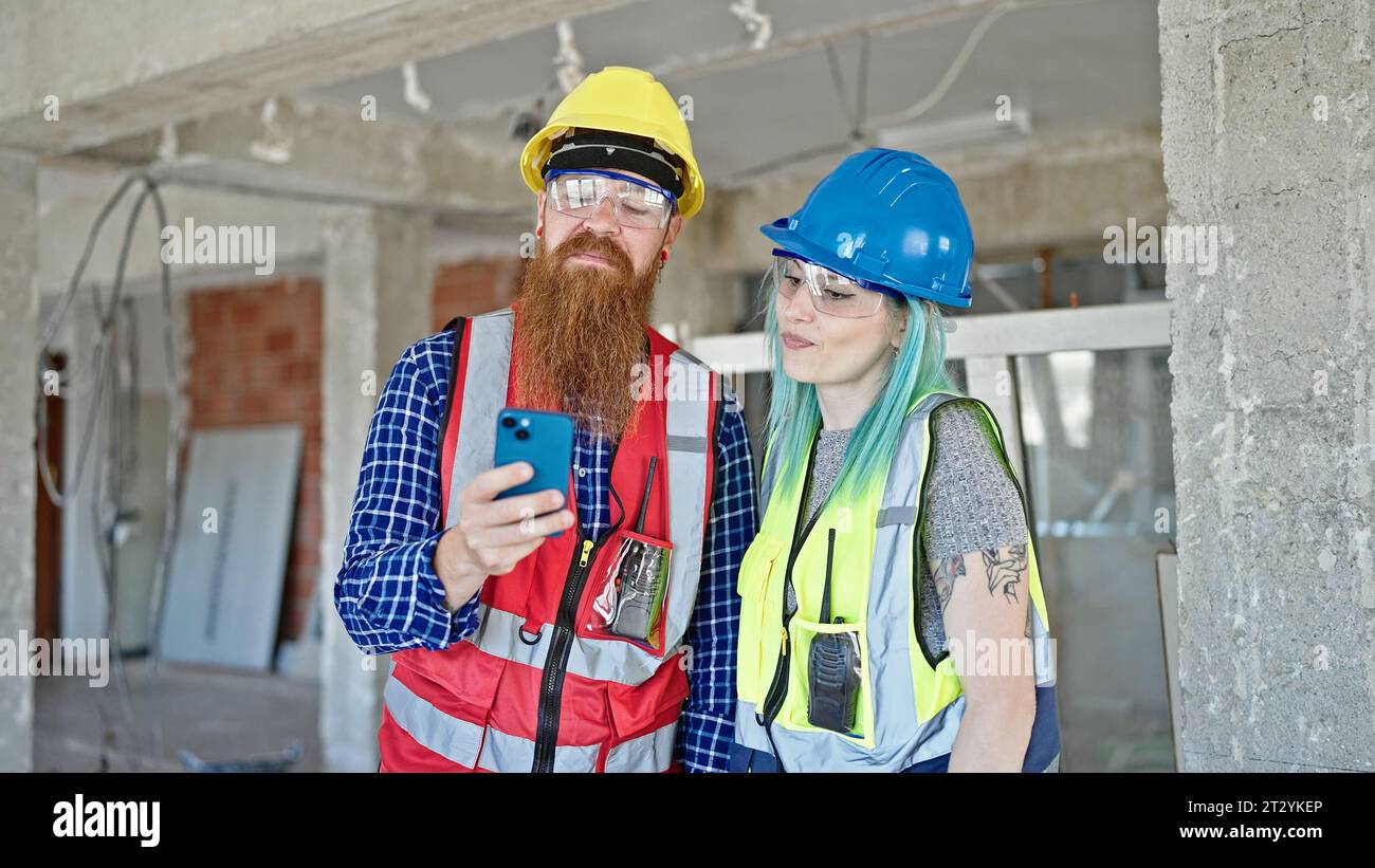 Man and woman builders using smartphone working at construction site Stock Photo