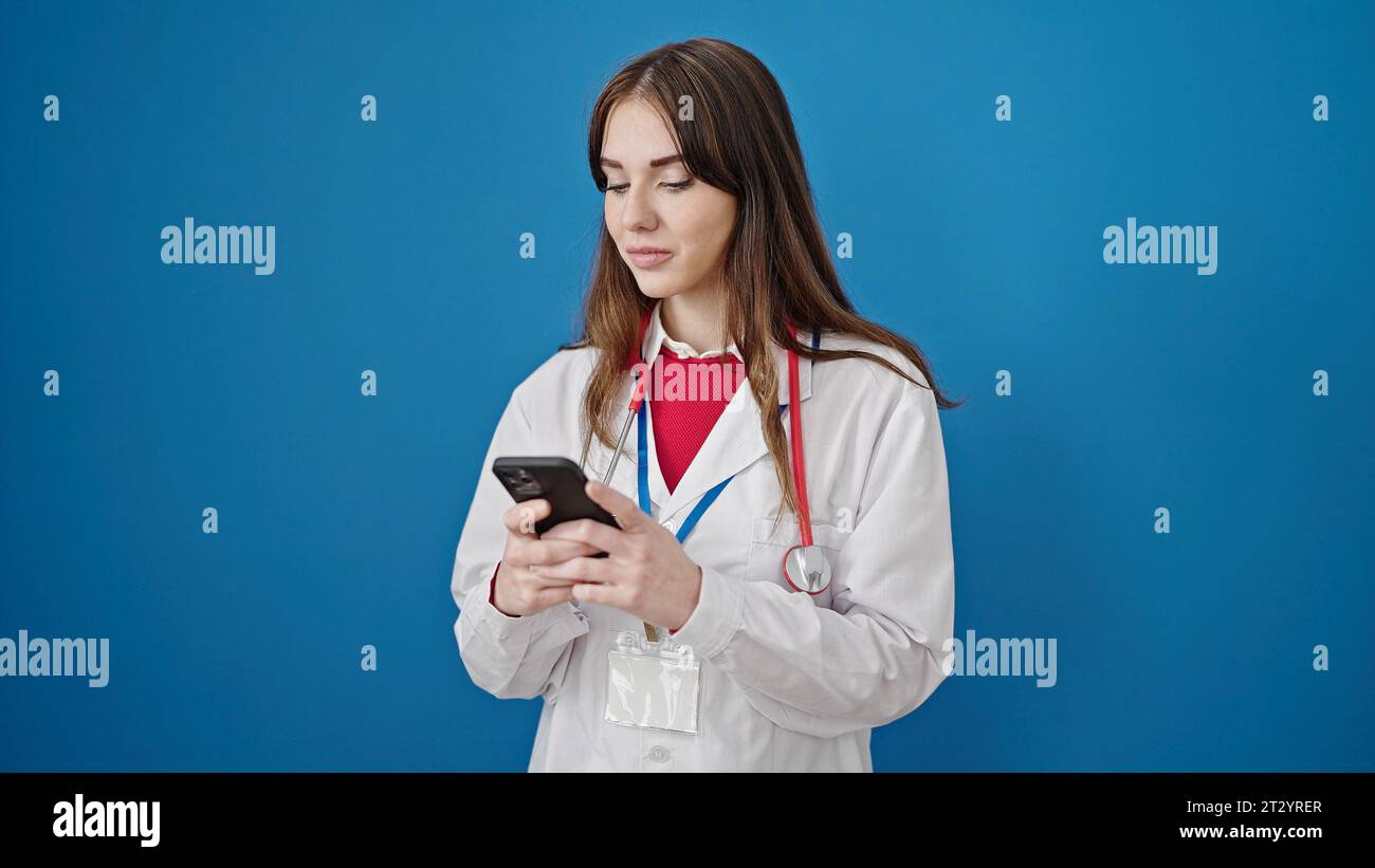 Young hispanic woman doctor using smartphone over isolated blue background Stock Photo
