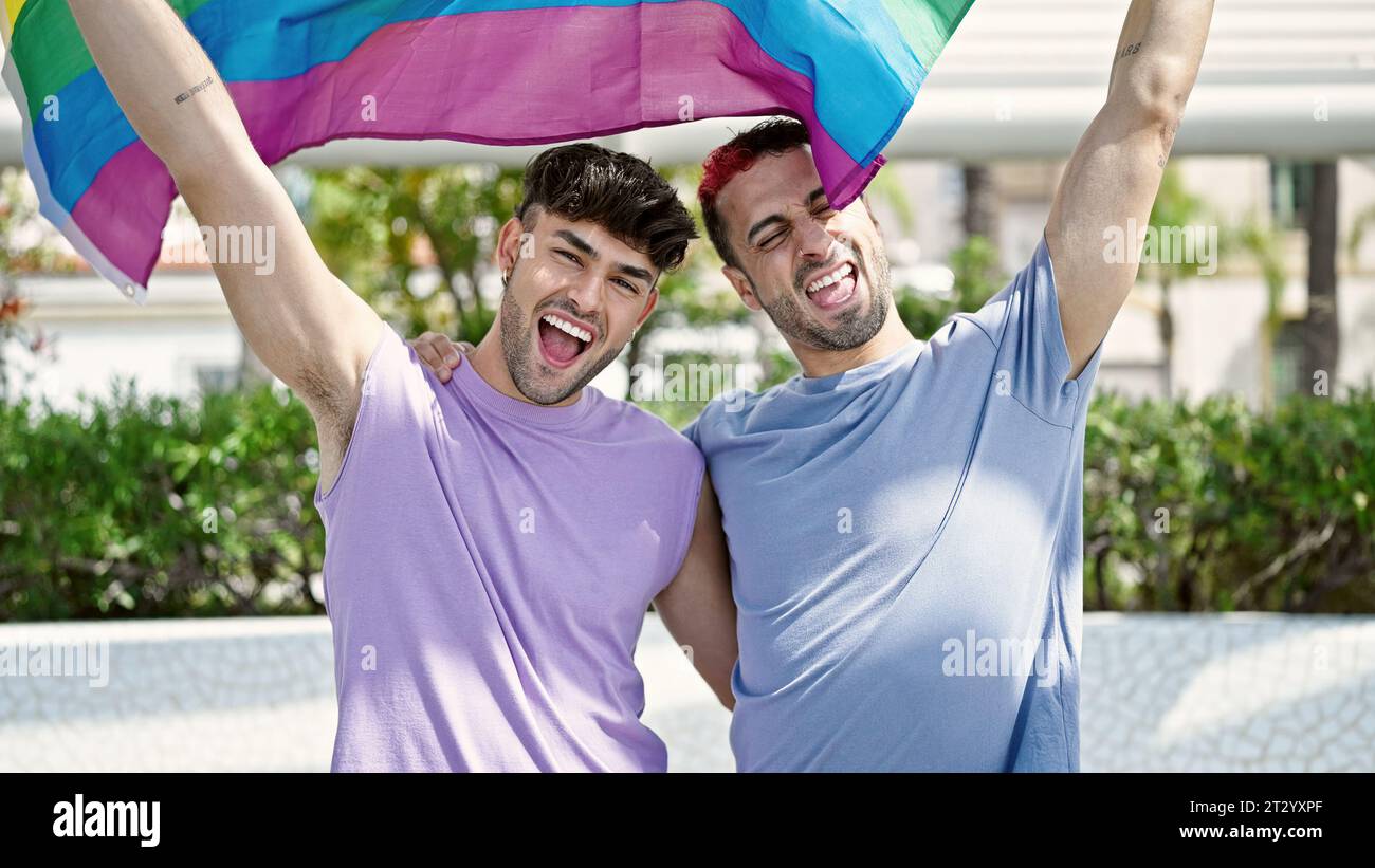 Two men couple hugging each other holding homosexual flag at park Stock ...