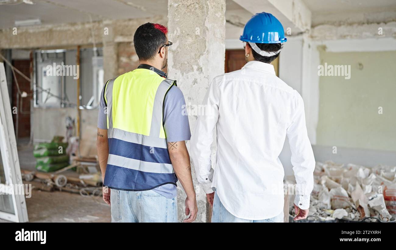 Two men builder and architect standing together backwards at construction site Stock Photo