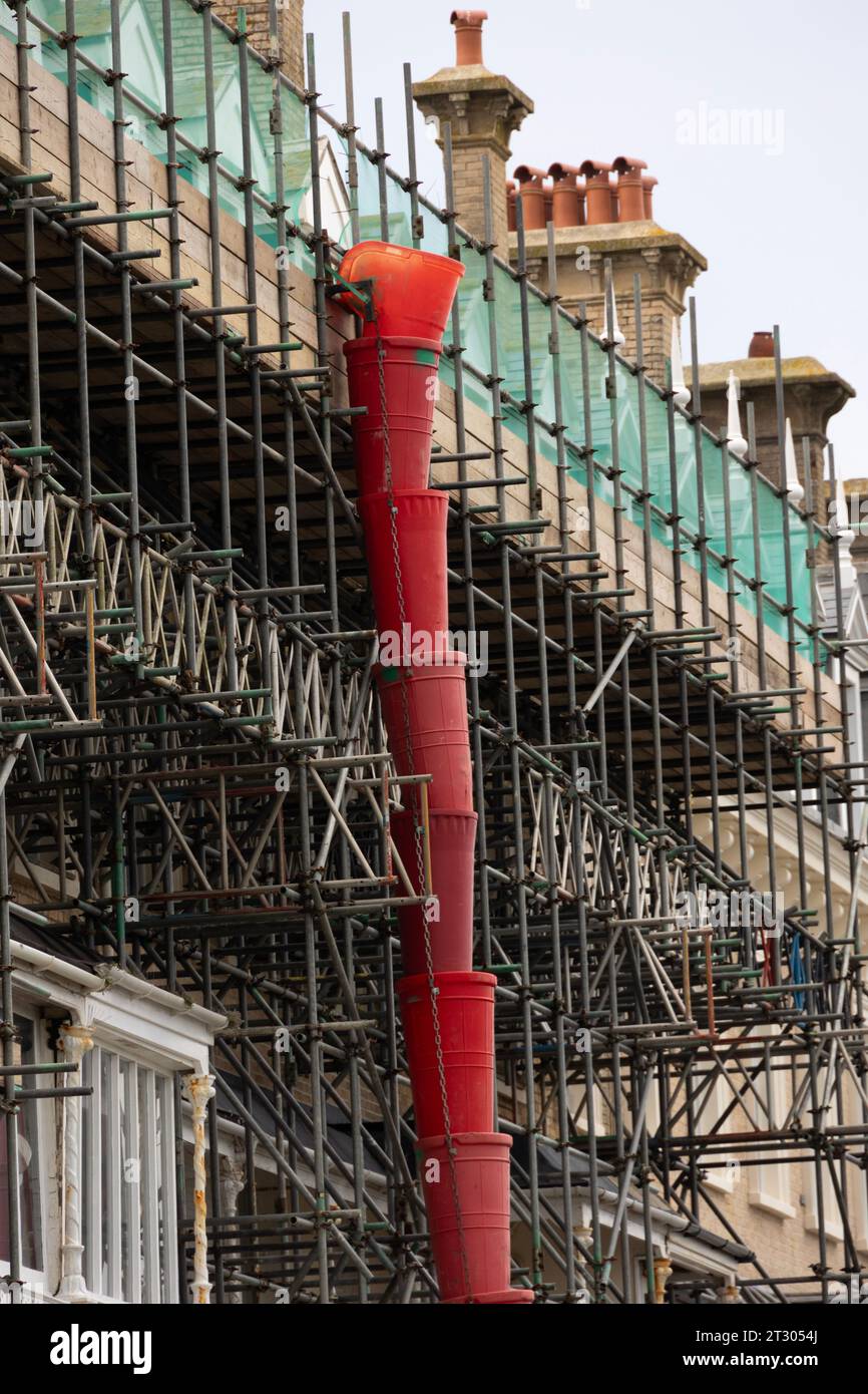 scaffolding and rubble chute at the side of a building in Worthing, West Sussex, UK Stock Photo
