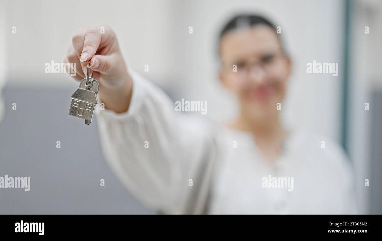 Young beautiful hispanic woman smiling holding new house keys at new ...