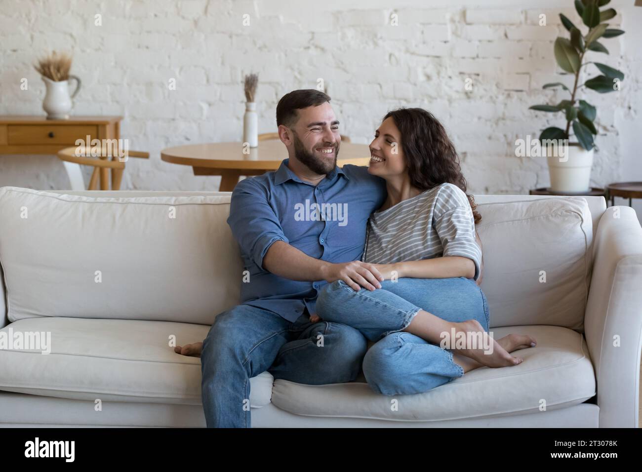 Joyful married couple relaxing on soft white home couch together Stock Photo