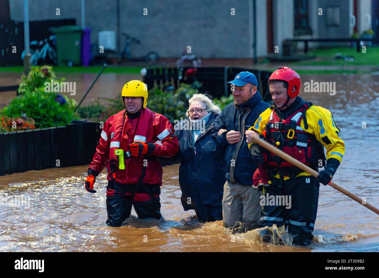 Woman is led to safety by coastguard in Brechin after the River South Esk broke flood defences during Storm Babet , Angus, Scotland, UK Stock Photo