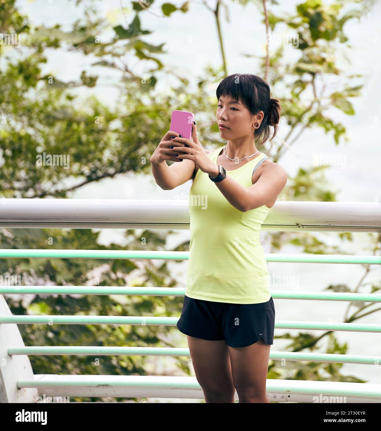 young asian woman taking a selfie outdoors using cellphone Stock Photo