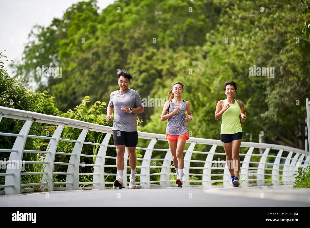 group of three asian young adult man and woman running jogging outdoors in park Stock Photo