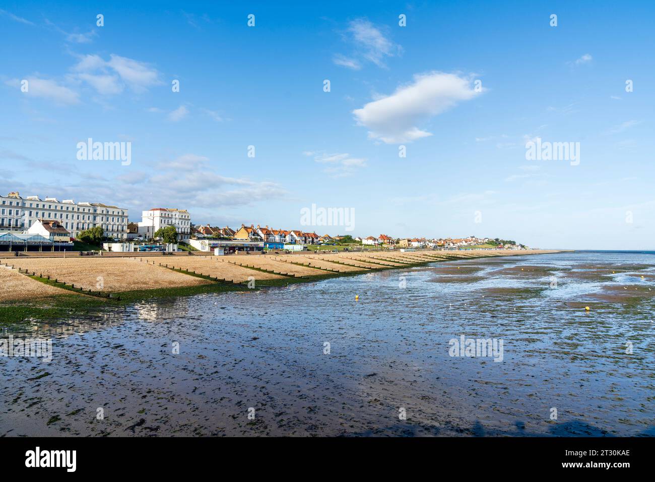 Early summer sunny morning view along the beach and groynes, breakwaters, on the empty beach at Herne Bay in kent against a clear blue sky. Stock Photo