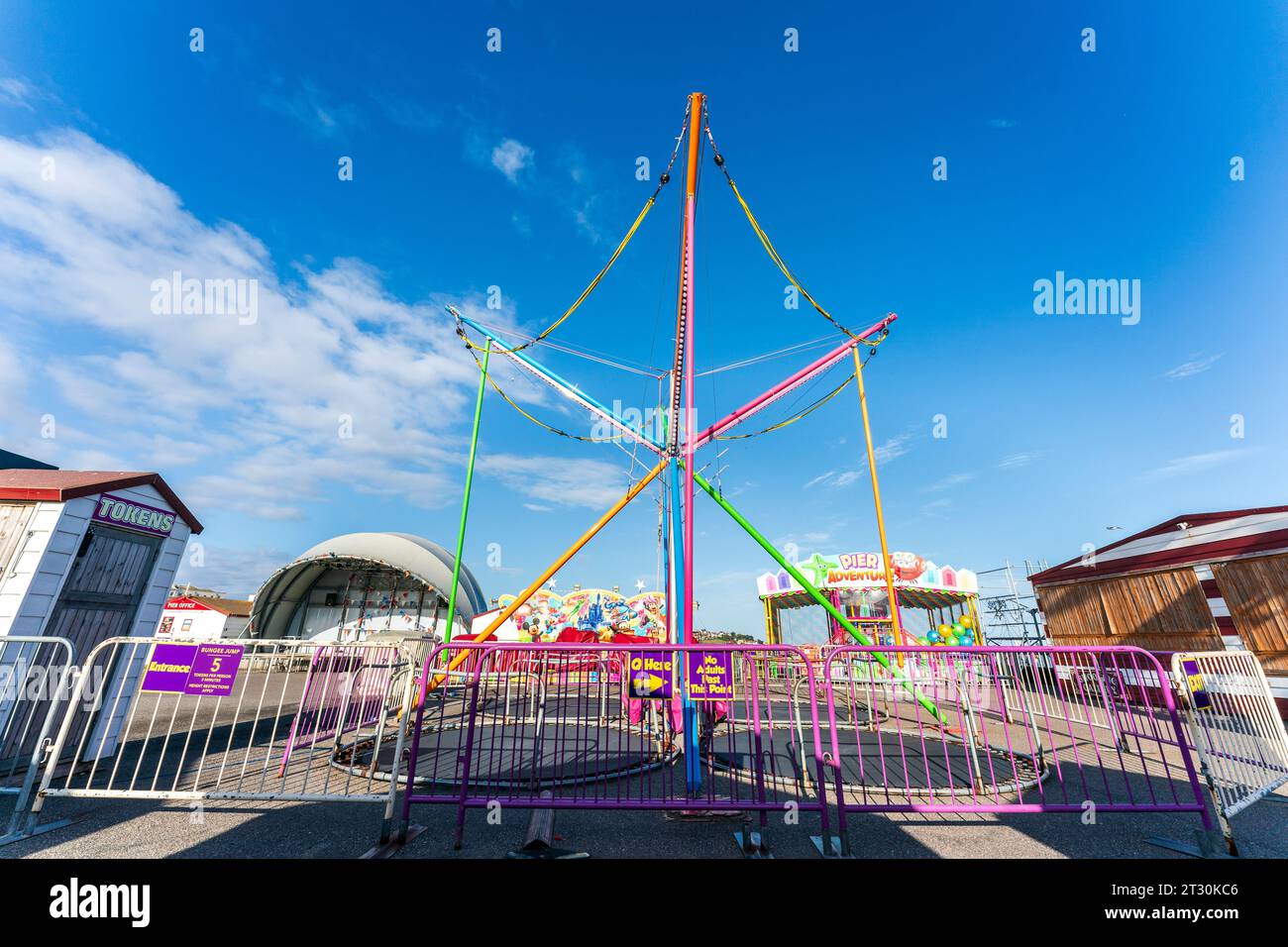 Empty funfair with bungee jump structure on the pier at Herne Bay in the early morning in the bright sunshine with a blue sky. Summertime. Stock Photo