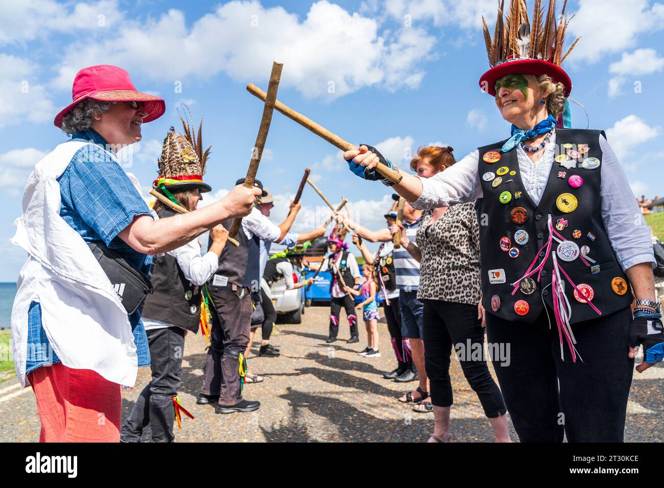 Dead Horse Morrismen holding sticks, dancing with members of the public on Herne Bay sea front during the summer. Bright sunshine and blue sky. Stock Photo