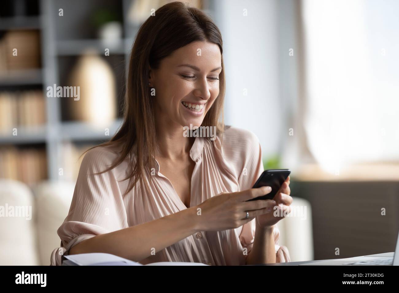 Smiling woman holding smart phone using on-line entertaining services Stock Photo