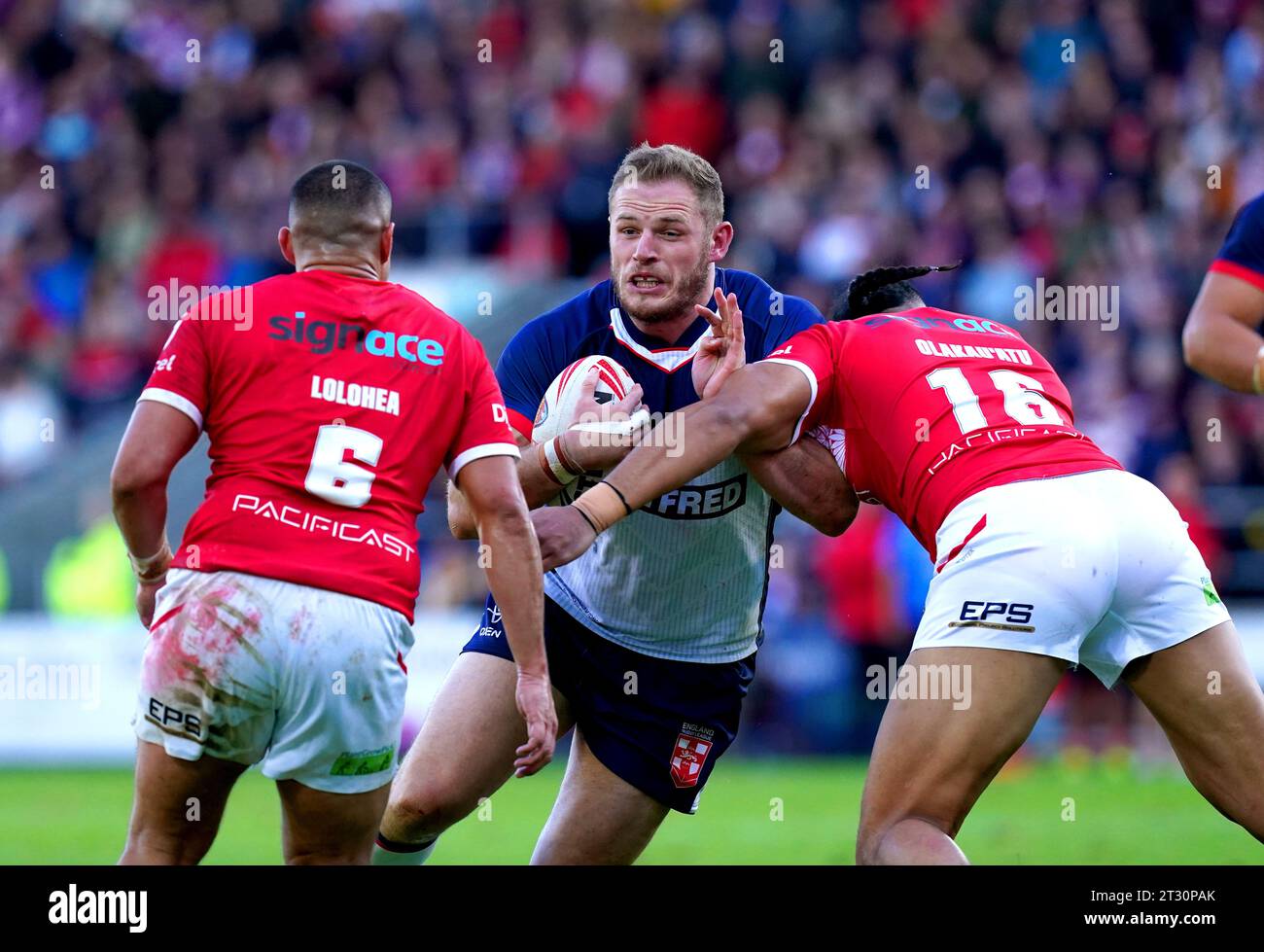 England's Tom Burgess (centre) is tackled by Tonga's Tuimoala Lolohea (left) and Haumole Olakau'atu during the International Test Series match at the Totally Wicked Stadium, St. Helens. Picture date: Sunday October 22, 2023. Stock Photo