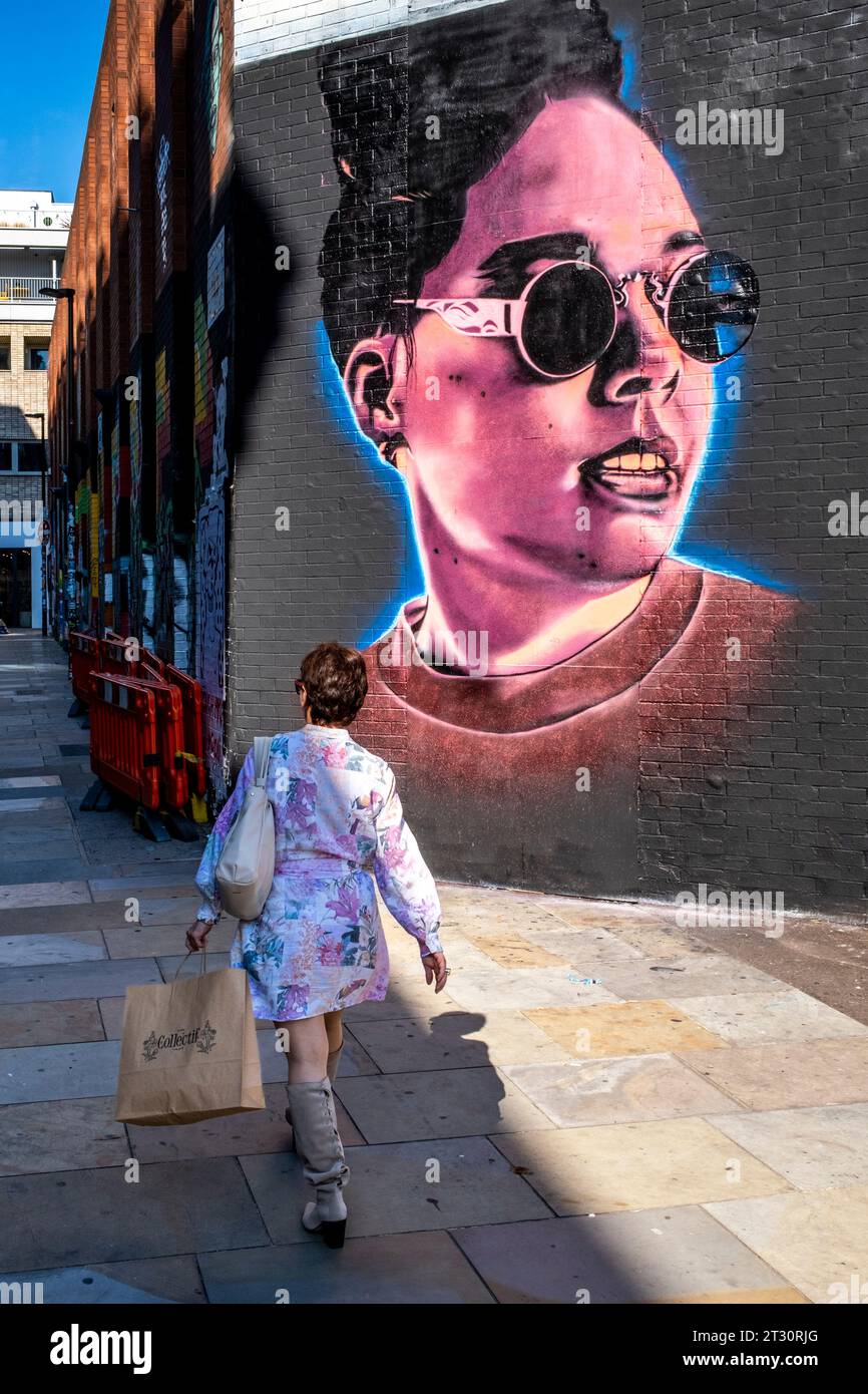 a-woman-walks-past-some-colourful-street-art-shoreditch-london-uk