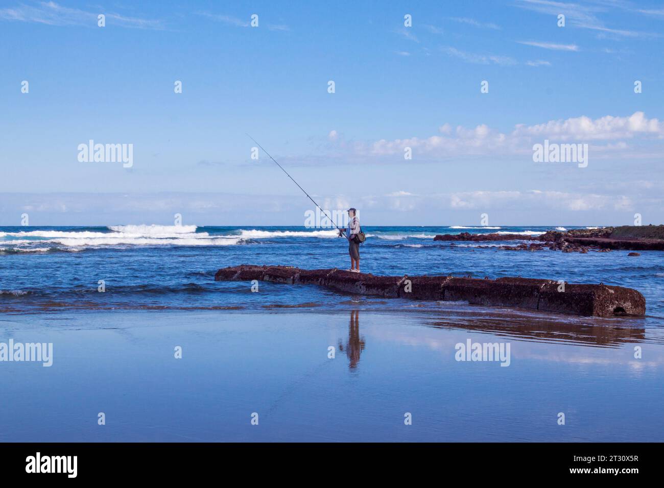 A fisherman fishing on Bocabarranco Beach in Gran Canaria, Spain Stock Photo