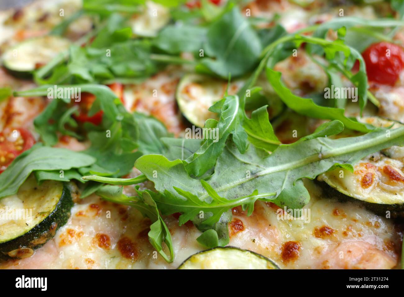 Delicious pizza with tomatoes, arugula leaves, zucchini and salmon Stock Photo