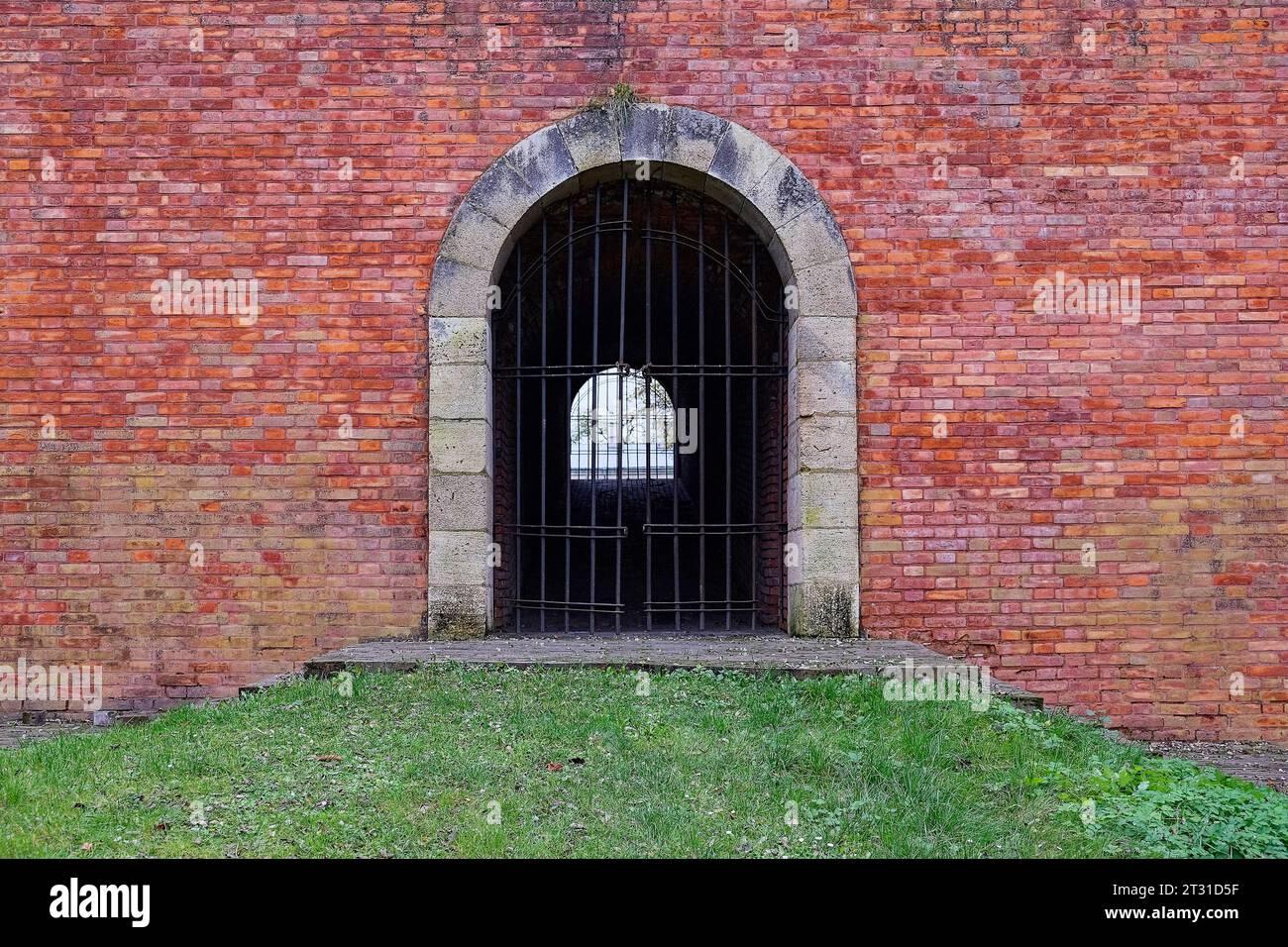 A passage closed by a lattice in an old brick fortress wall. Antique brickwork. Stock Photo