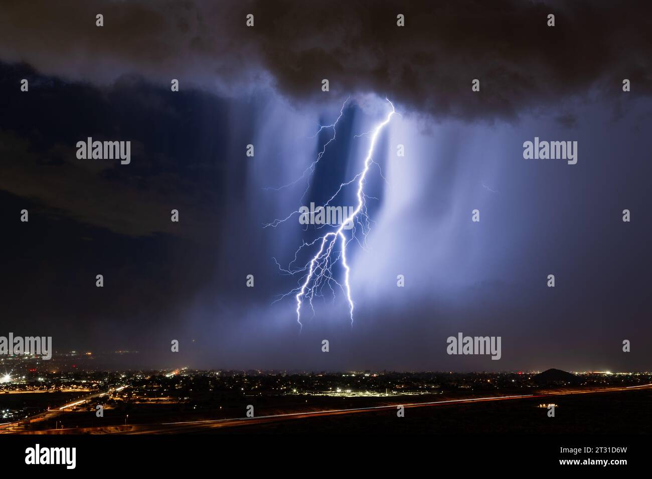 A powerful lightning bolt strikes through a microburst in a storm over