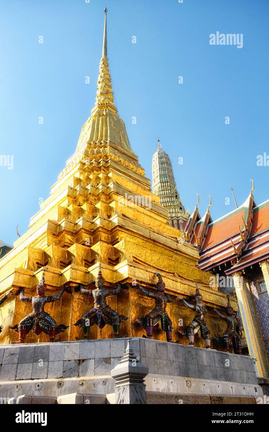 A golden temple spire in Thailand, supported by statues of mythical