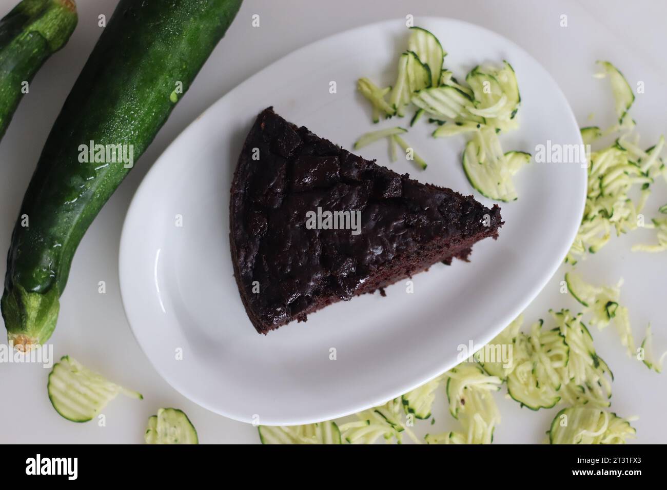 Slice of Zucchini chocolate cake. Moist double chocolate cake with grated zucchini, coco powder, chocolate and chocolate chips. Shot on white backgrou Stock Photo