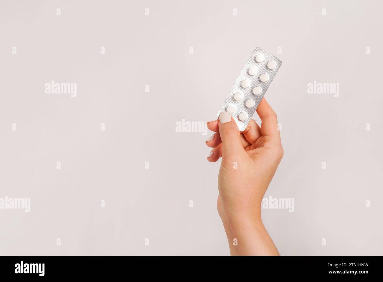 Hand holding medicine pills on a light gray background. copy space Stock Photo
